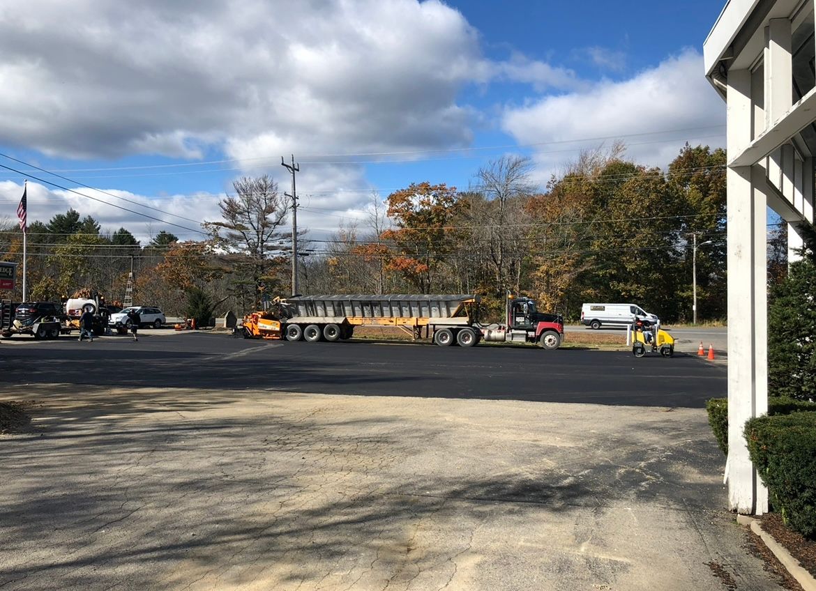 Construction site with trucks and workers on a gravel lot under a blue sky