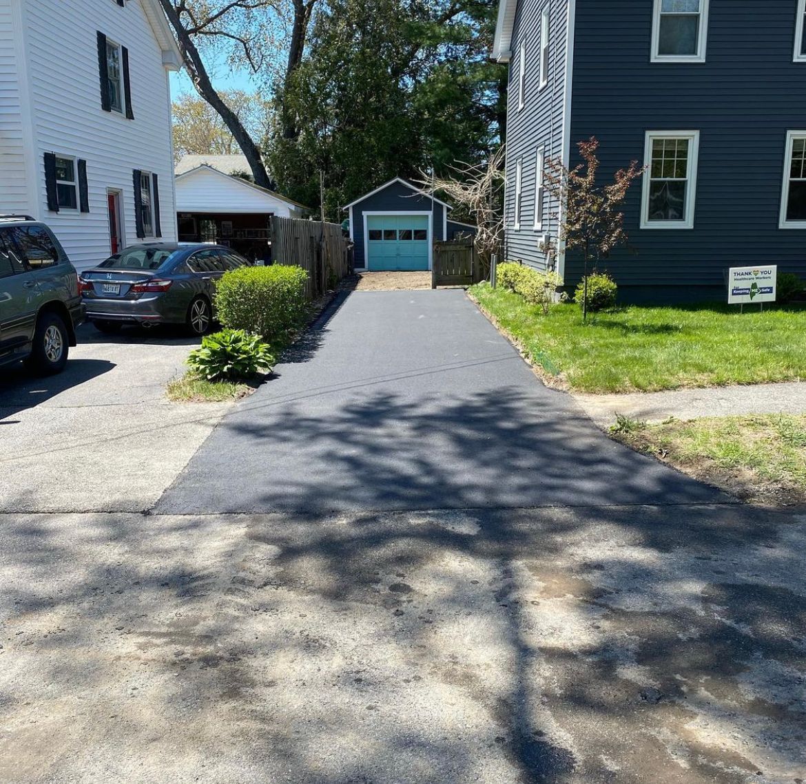 Residential driveway leading to a detached garage between two houses on a sunny day