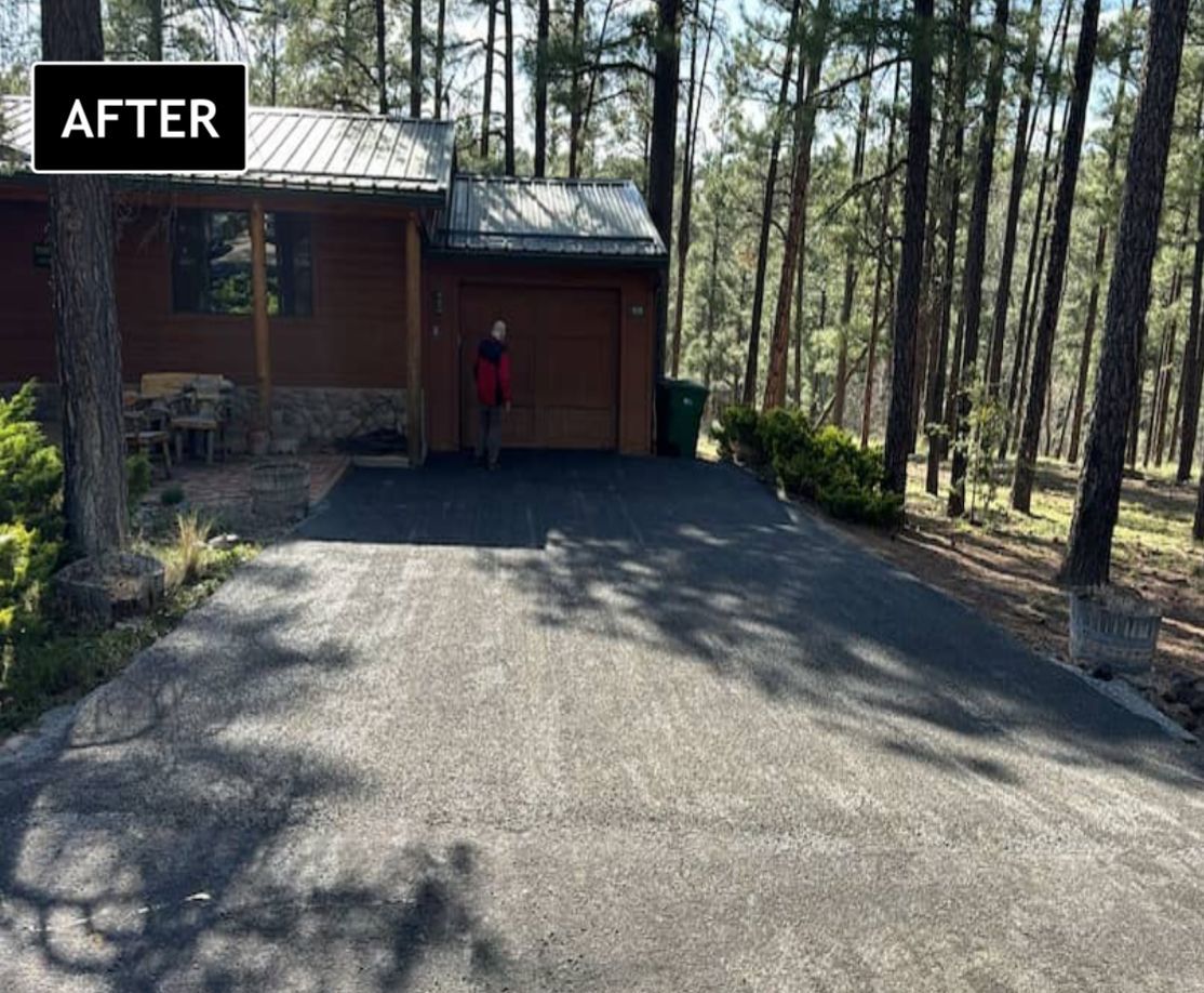 After view of a house with a newly paved driveway in a wooded area