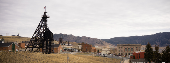 Industrial mine headframe in a small town with hills and a cloudy sky in the background