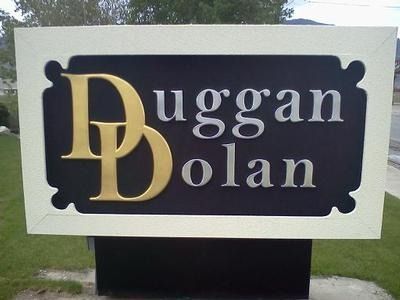 Duggan Dolan sign with gold lettering on a dark plaque outdoors.