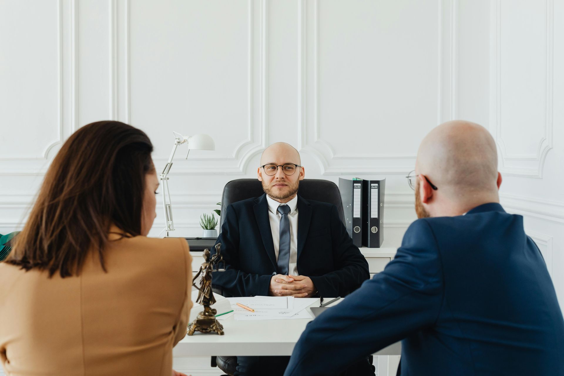 Business meeting with three people seated around a white table in a bright office