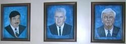 Three framed portraits of men in suits, each with a blue background.