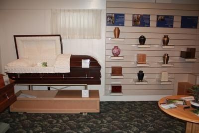 Funeral home interior with open casket, urns, and brochures.