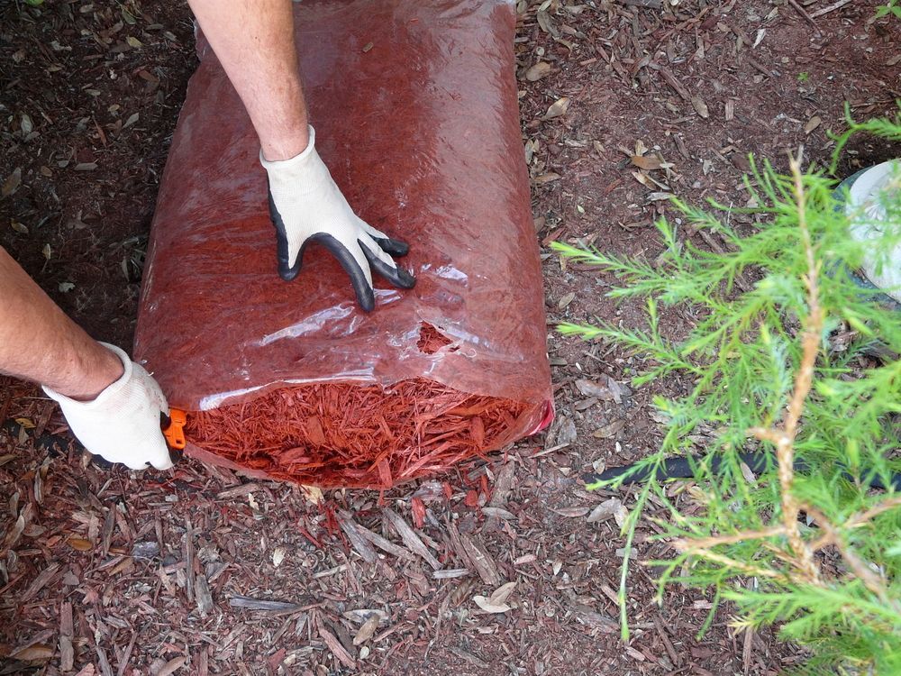A Person Wearing Gloves is Holding a Bag of Mulch — Hothams In Bathurst, NSW