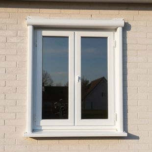 White double-casement window with a shutter box installed on a light-colored brick wall.