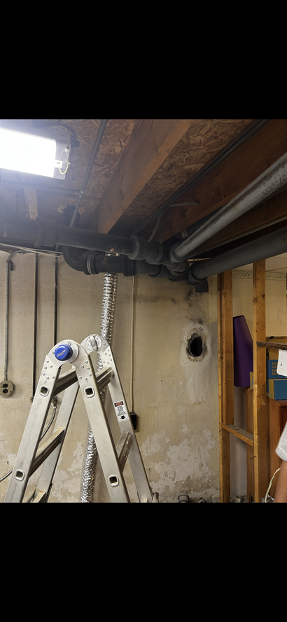 Technician adjusting industrial pipes and gauges while another observes with a clipboard.