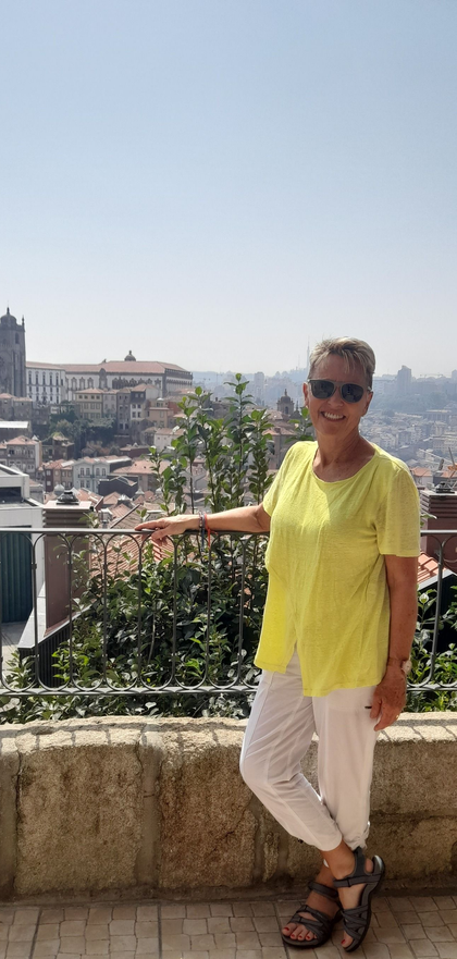 Person in a bright yellow shirt posing on a terrace overlooking a cityscape.