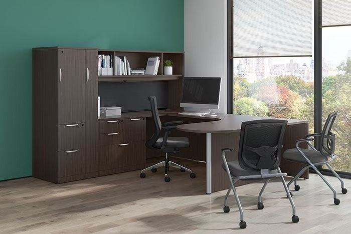 A room with a desk , chairs , and a computer.