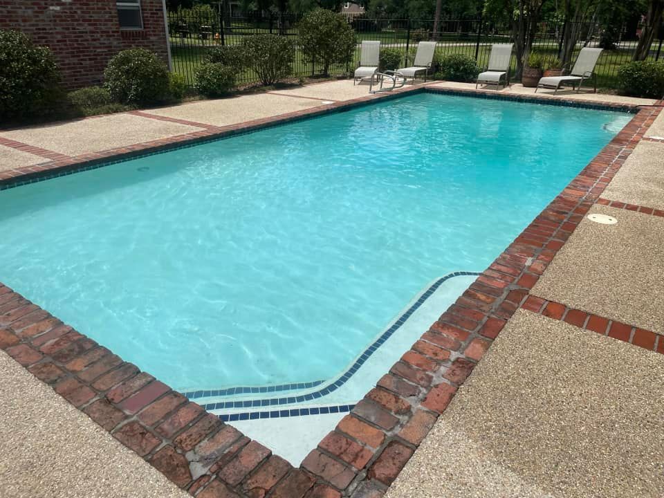 Rectangular outdoor swimming pool with blue water, brick coping, and pool steps in the corner