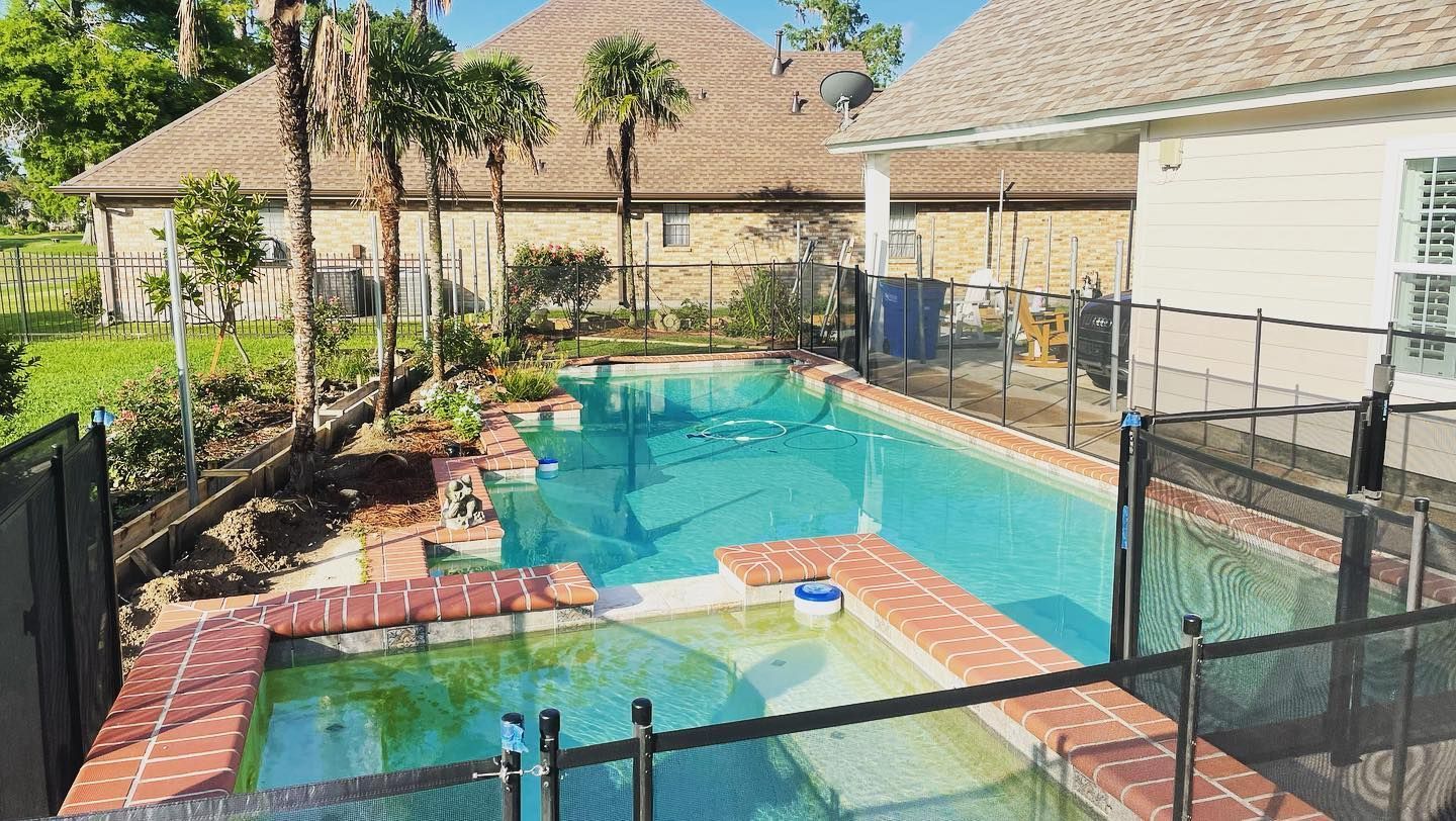 Backyard swimming pool with turquoise water, brick edging, and palm trees beside a house.