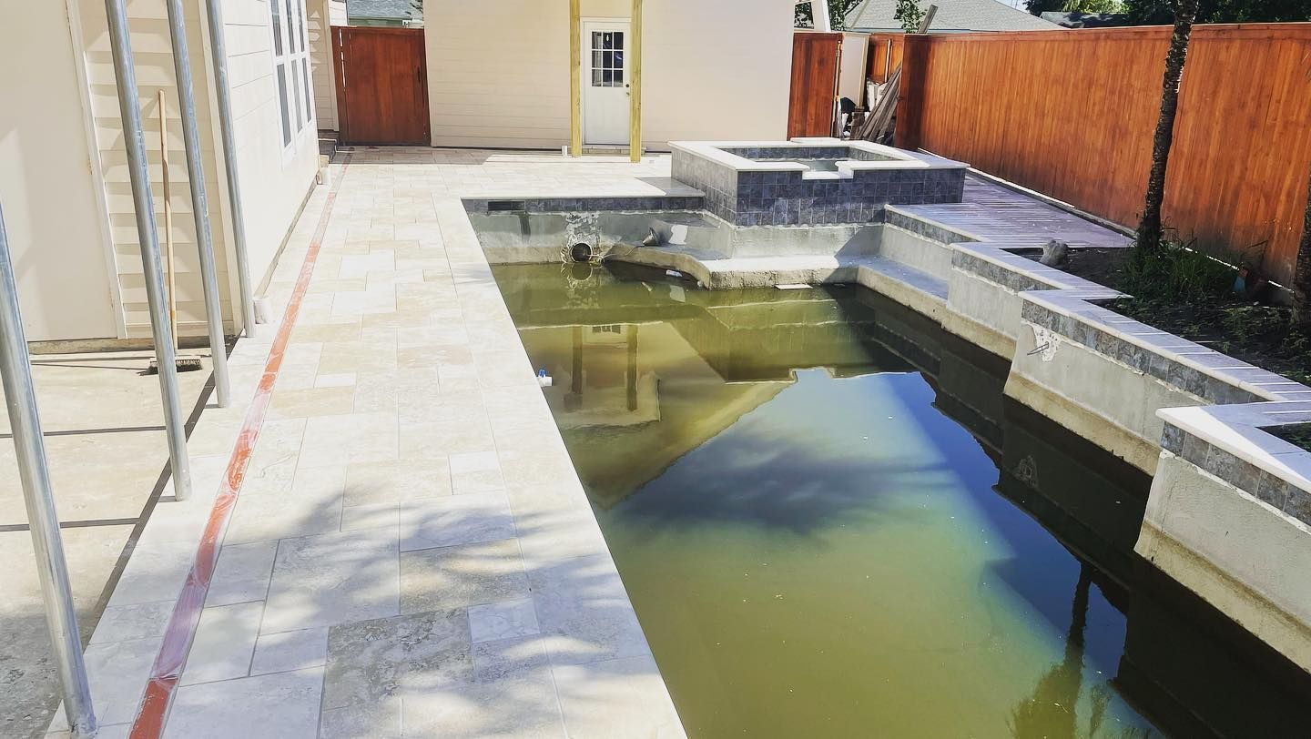 Narrow backyard with a murky pool, concrete deck, and orange privacy fence beside a house