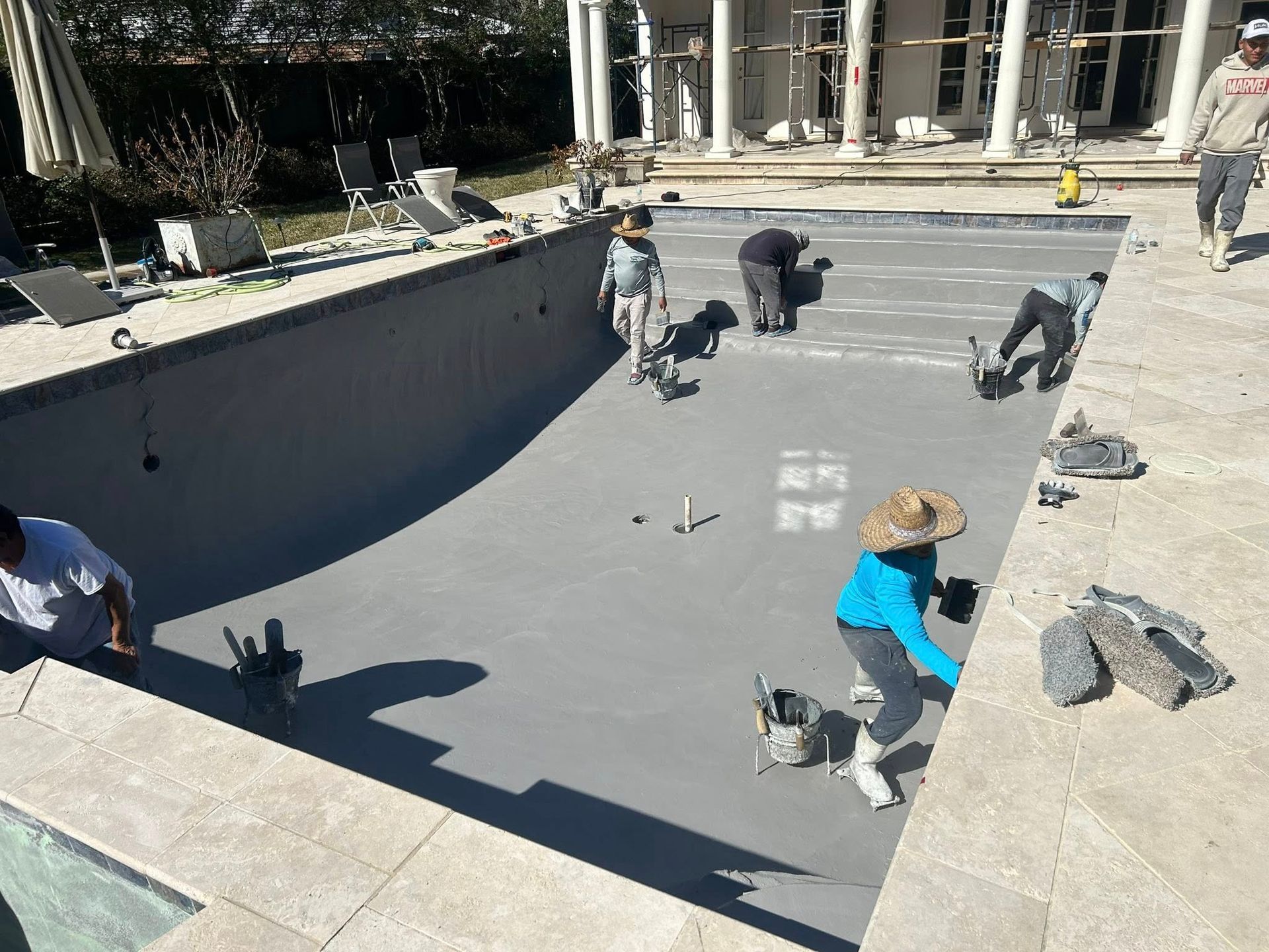 Workers troweling concrete in a large skatepark bowl under construction