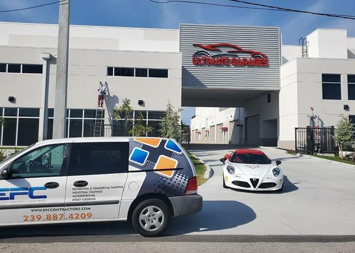 White Alfa Romeo sports car and EFC van parked in front of a building, with a person painting the facade.