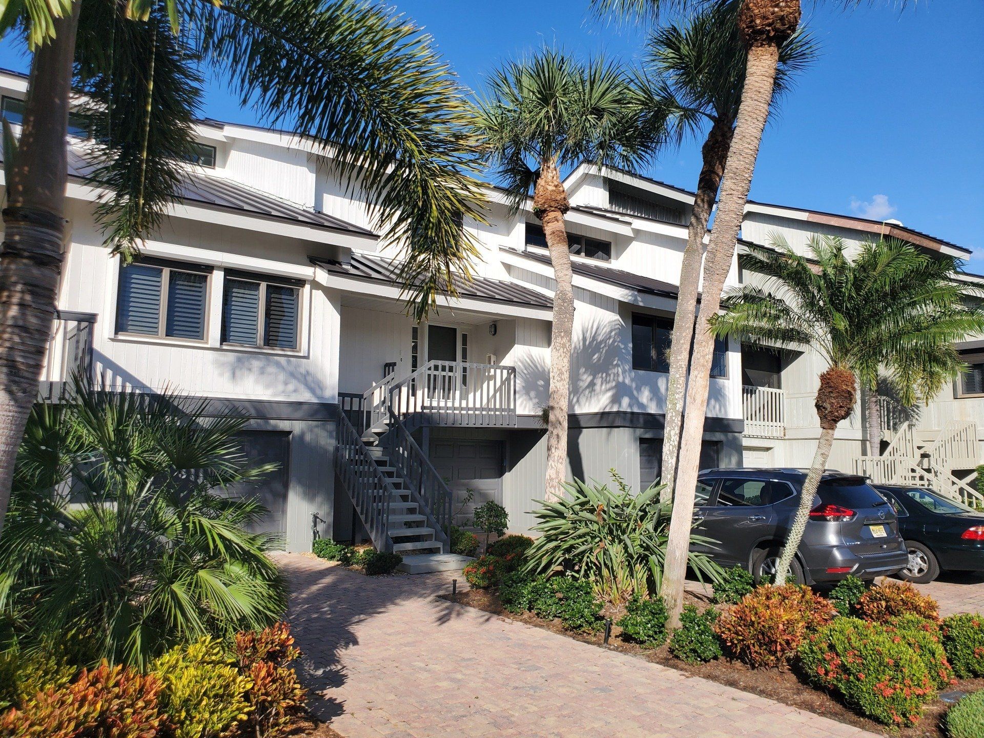 Townhouses with a gray and white exterior, palm trees, and a walkway.