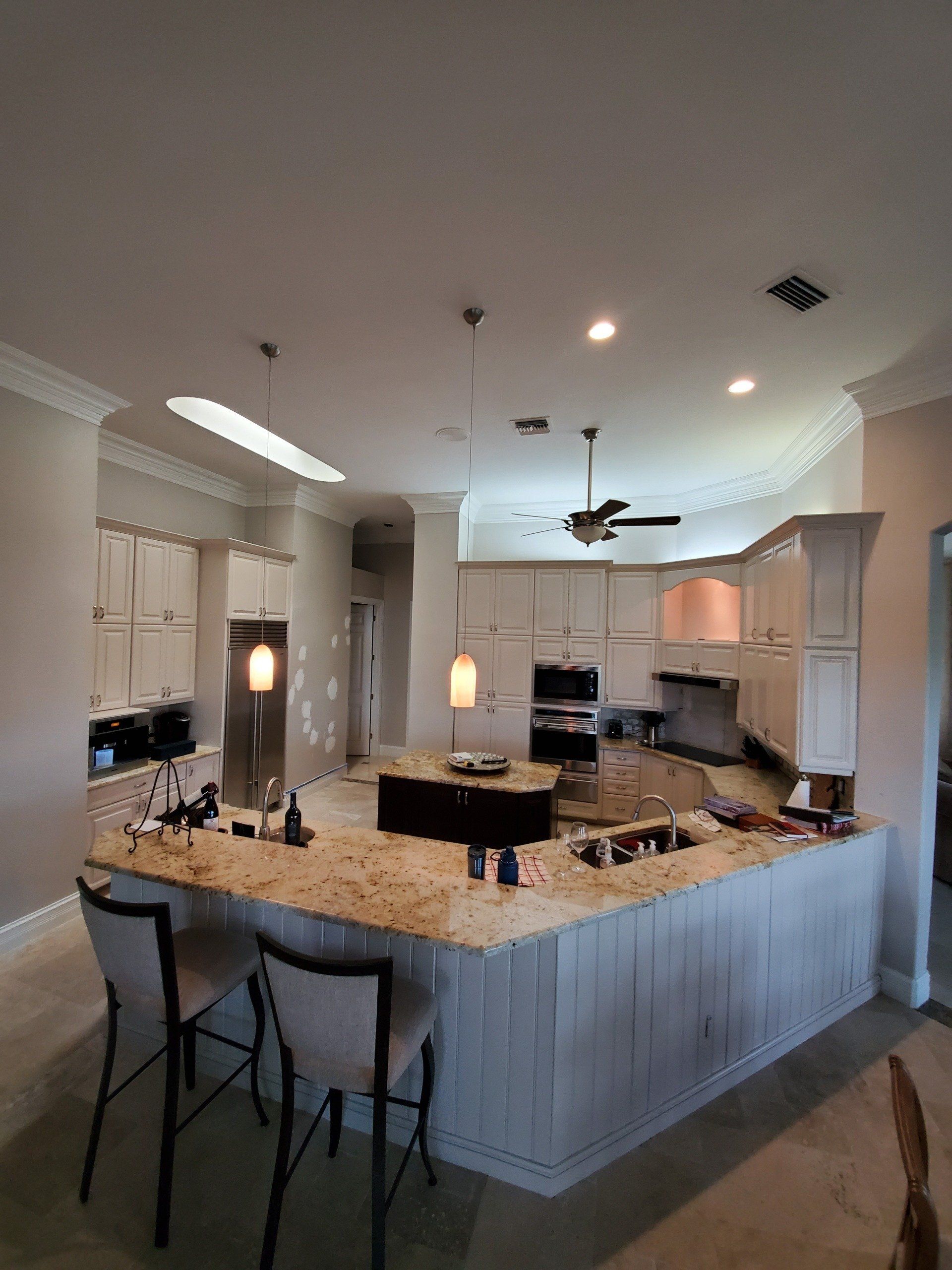 Spacious kitchen with light-colored cabinets, granite countertops, and a large island with seating.