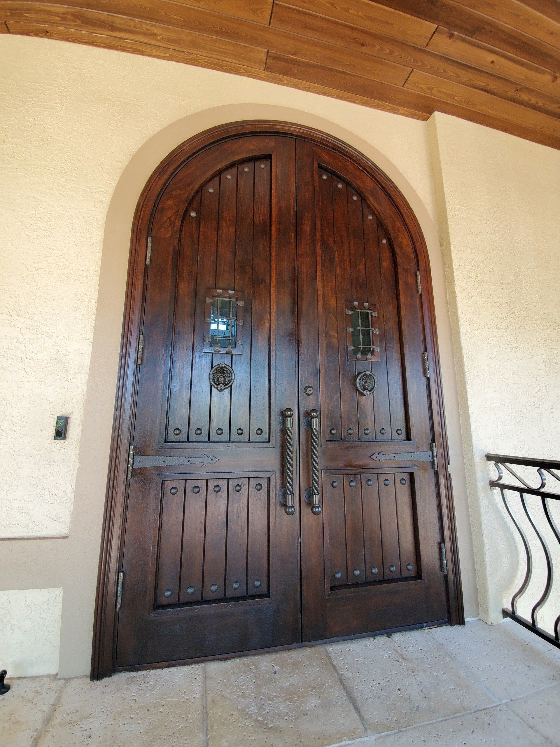 Wooden arched double doors with ornate hardware.