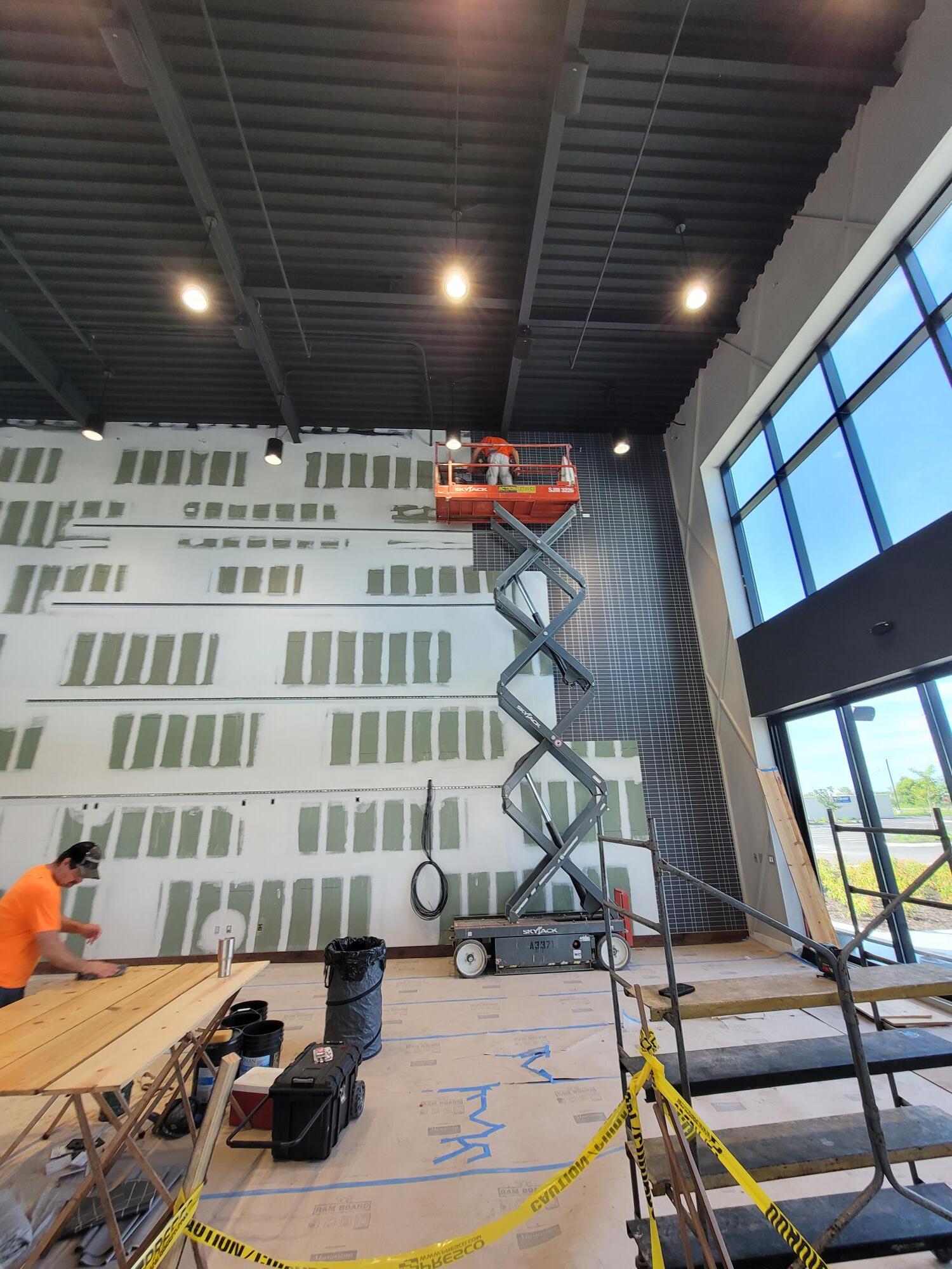 Construction site: Workers on a lift and on the ground installing wall panels.