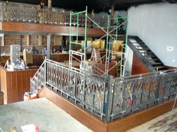 Interior construction site with metal railings, stairs, and scaffolding.