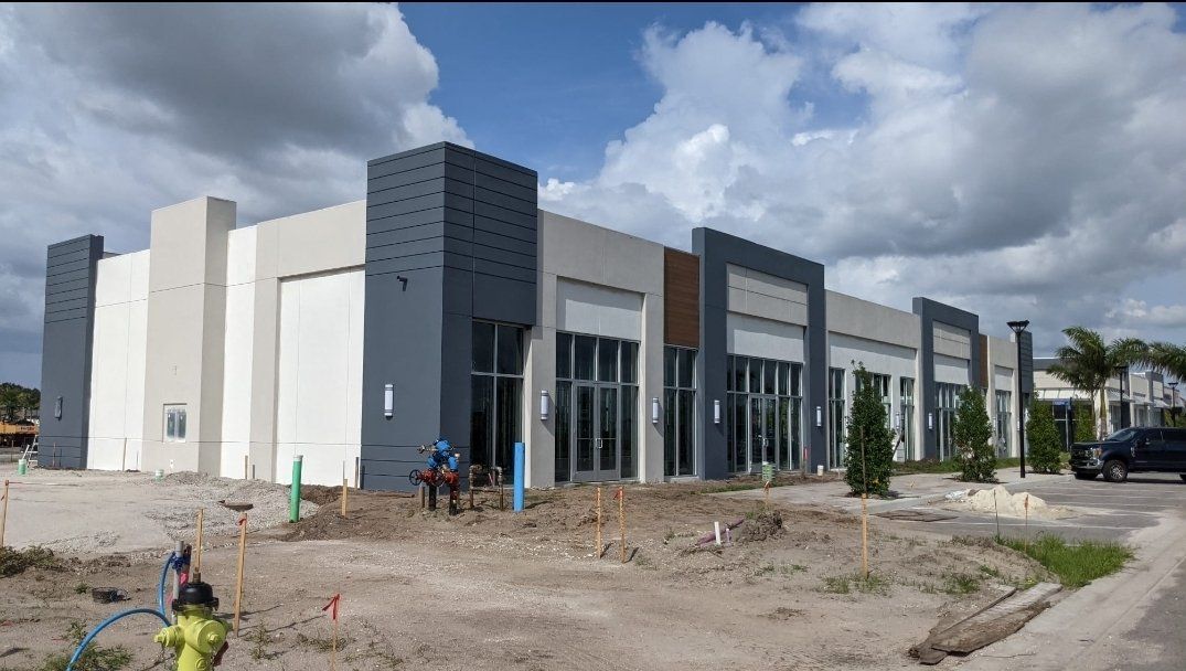 New commercial building under construction, featuring grey and white facade with large windows and blue accents.