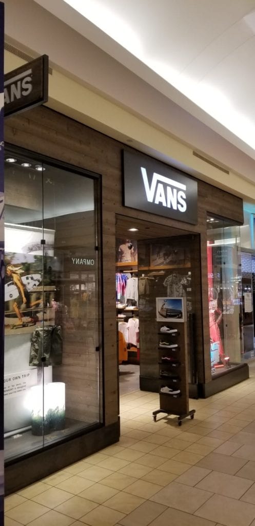 Vans store front in a mall. Dark brown wood siding with the Vans logo in white.