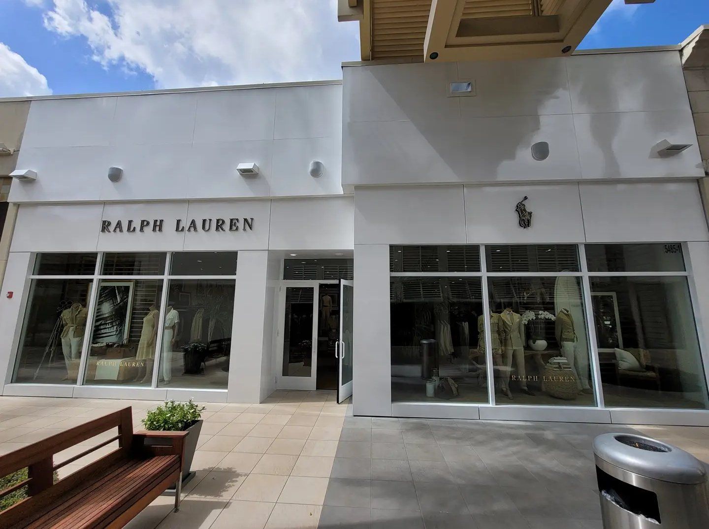Ralph Lauren store front, white exterior, glass windows, open door, gray pavement.