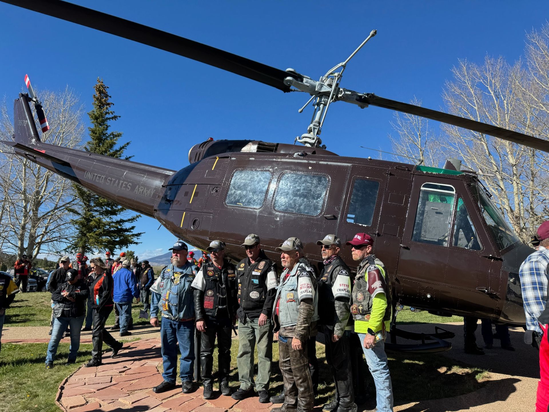 A group of men are standing in front of a helicopter.