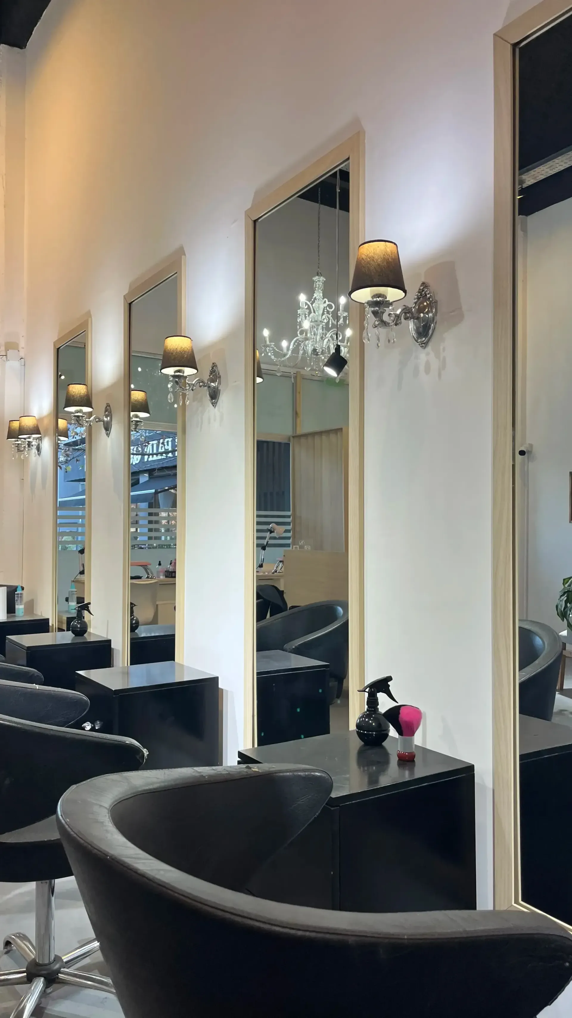 Interior del salón con sillones de peluquería negros, espejos en las paredes