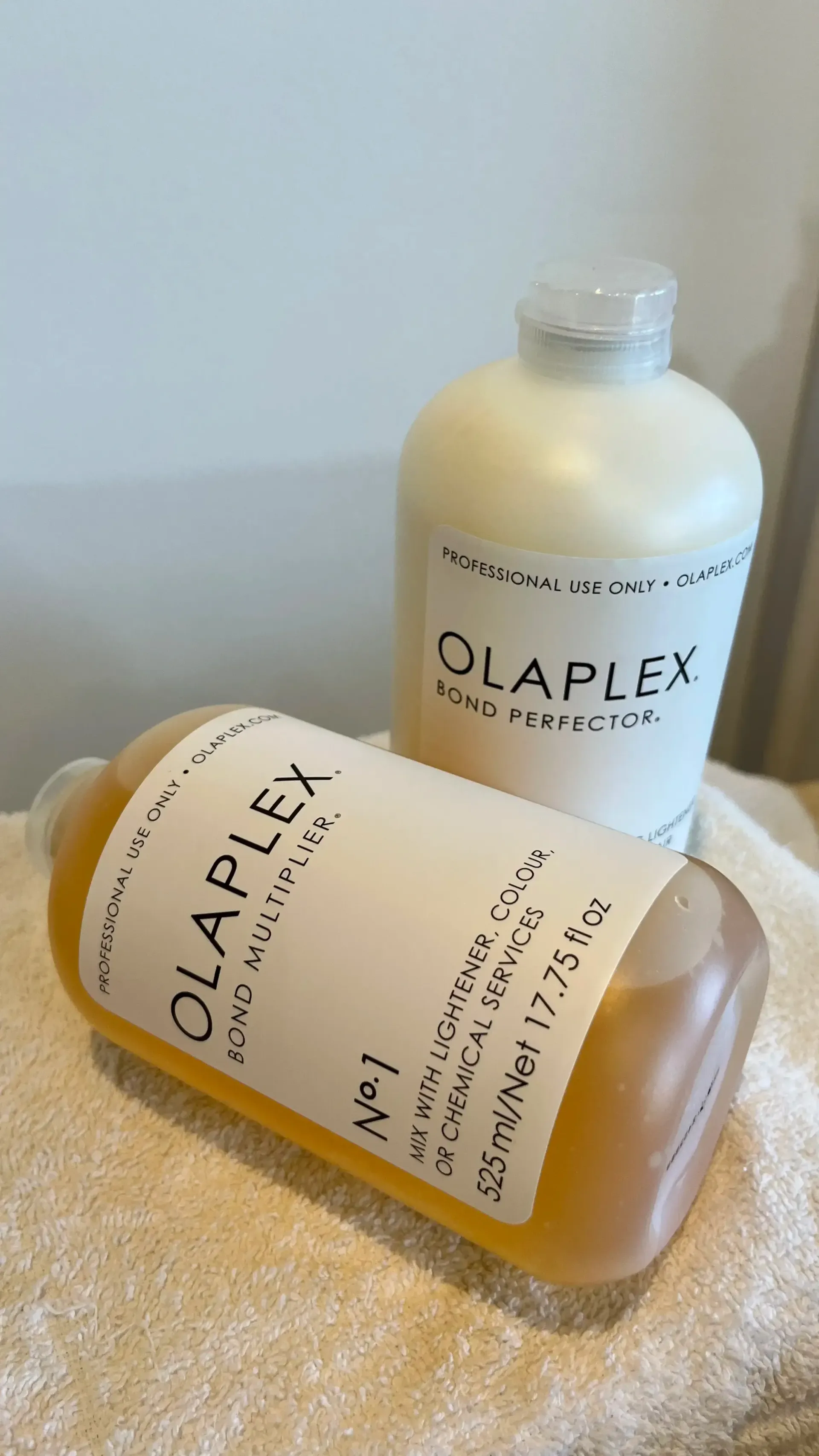 Dos frascos de Olaplex sobre una toalla blanca, uno en posición vertical y otro tumbado.