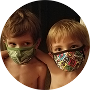 Two children wearing patterned face masks, looking at the camera inside a circular frame