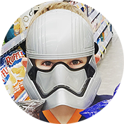 Person wearing a white hard hat and gray respirator mask in front of store shelves