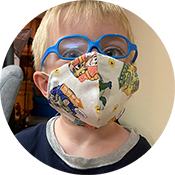 Child wearing blue glasses and a colorful face mask with animal prints