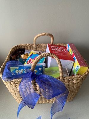 Wicker basket filled with assorted snacks and a blue ribbon bow.