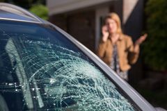 Shattered windshield on a car with a blurred person standing in the background