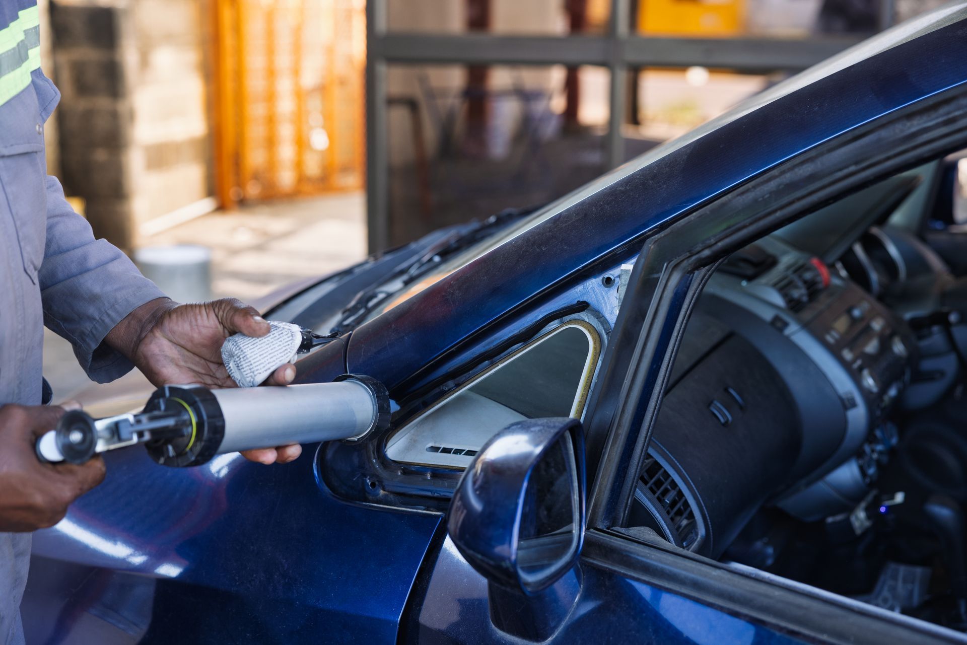 Person polishing a blue car door with a buffer in an auto shop