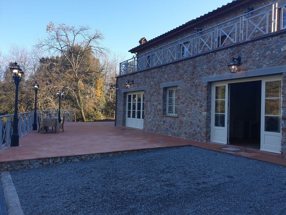 Edificio in pietra con porte aperte, patio e vialetto di ghiaia.