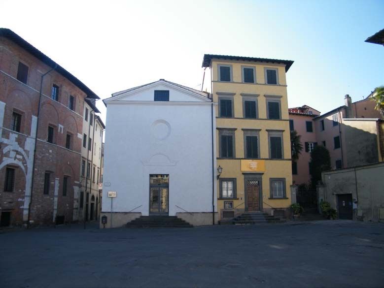 Edifici di varie altezze e colori in una piazza soleggiata.