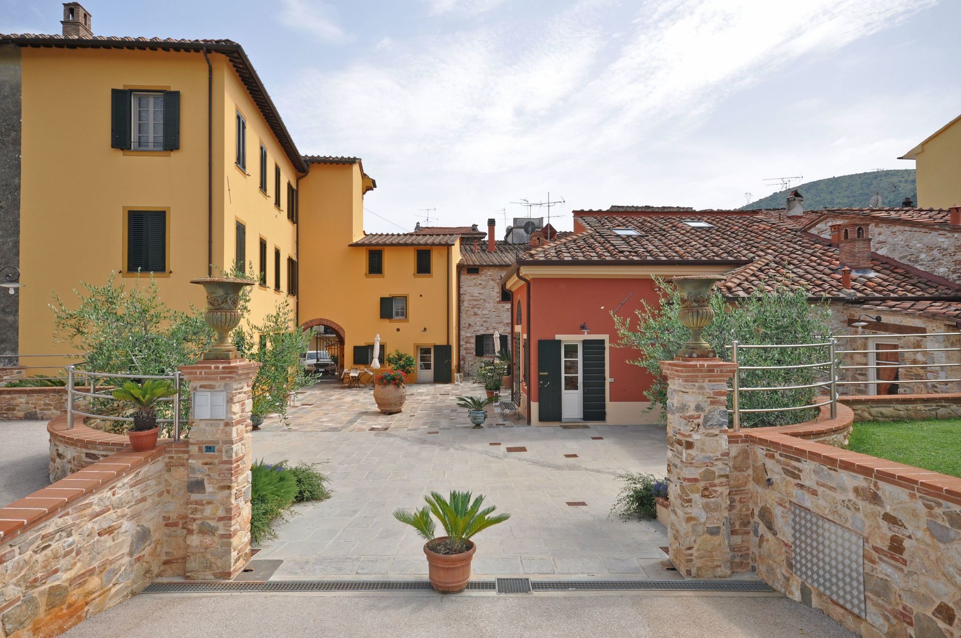 Un cortile con vari edifici colorati, piante in vaso e dettagli in mattoni.