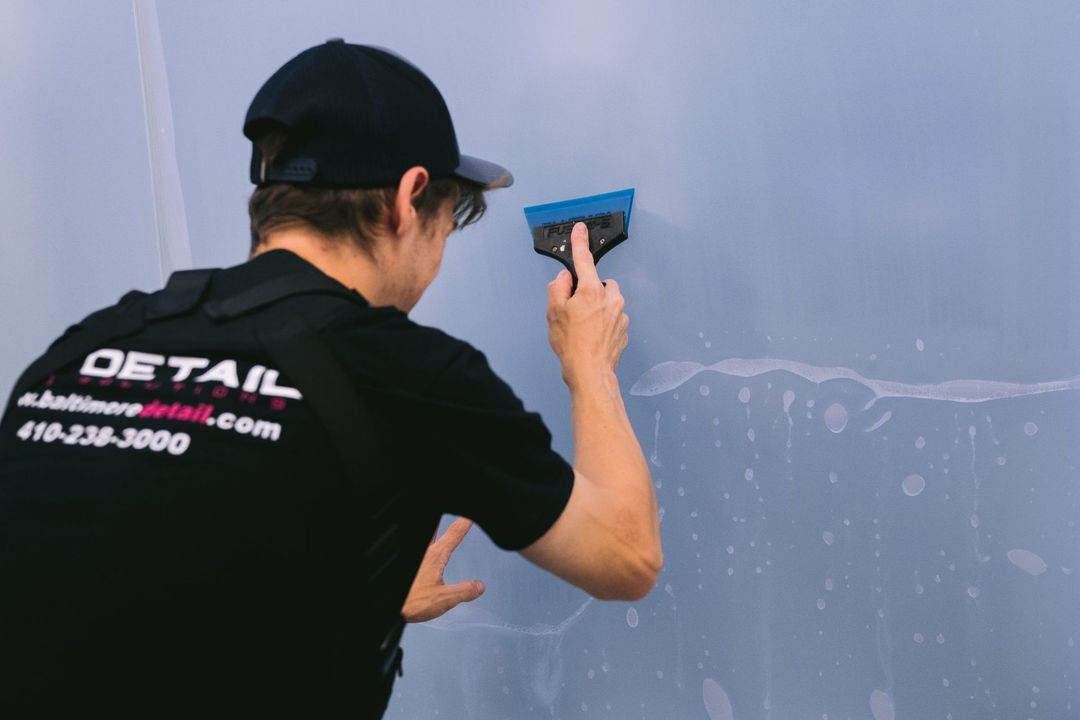 Worker using a blue squeegee on a gray wall surface during cleaning or preparation 작업