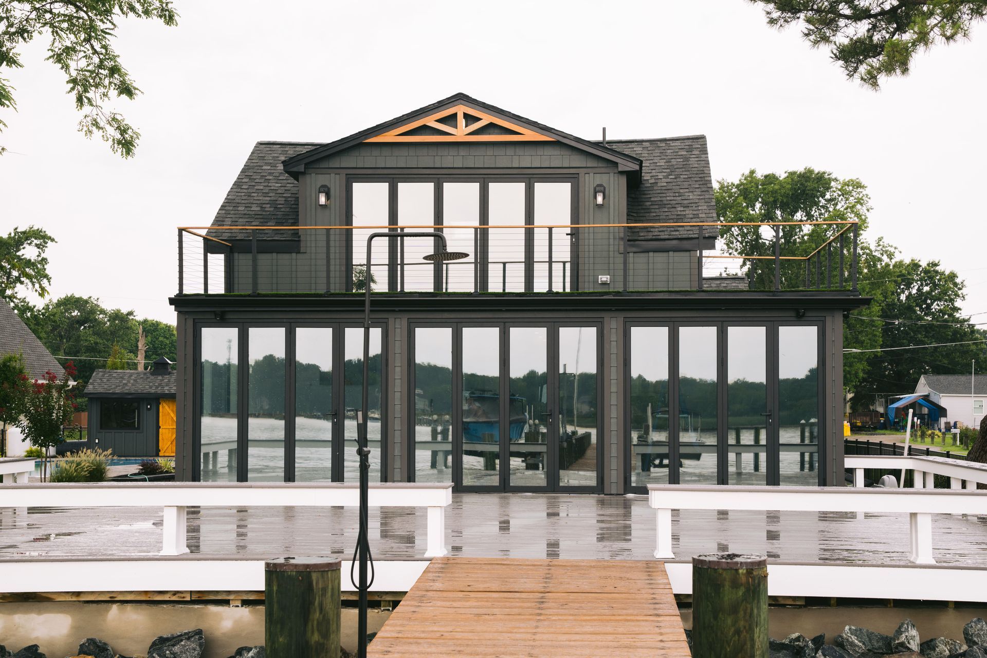 Modern gray waterfront house with large windows and a white dock in front