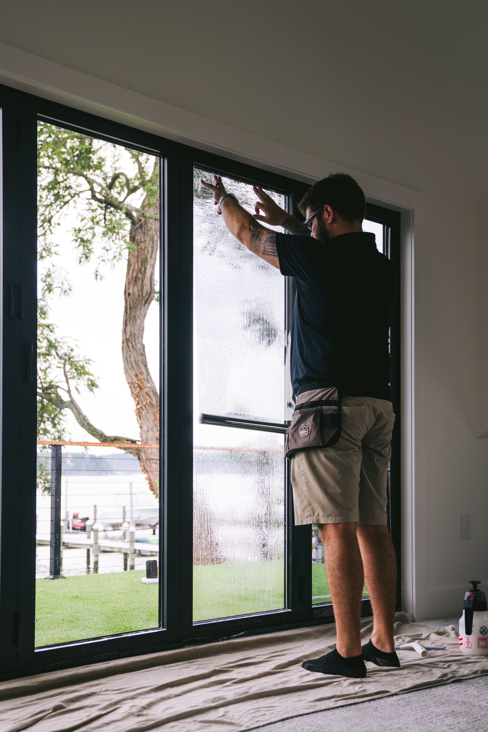 Worker installing a large glass sliding door in a room under construction