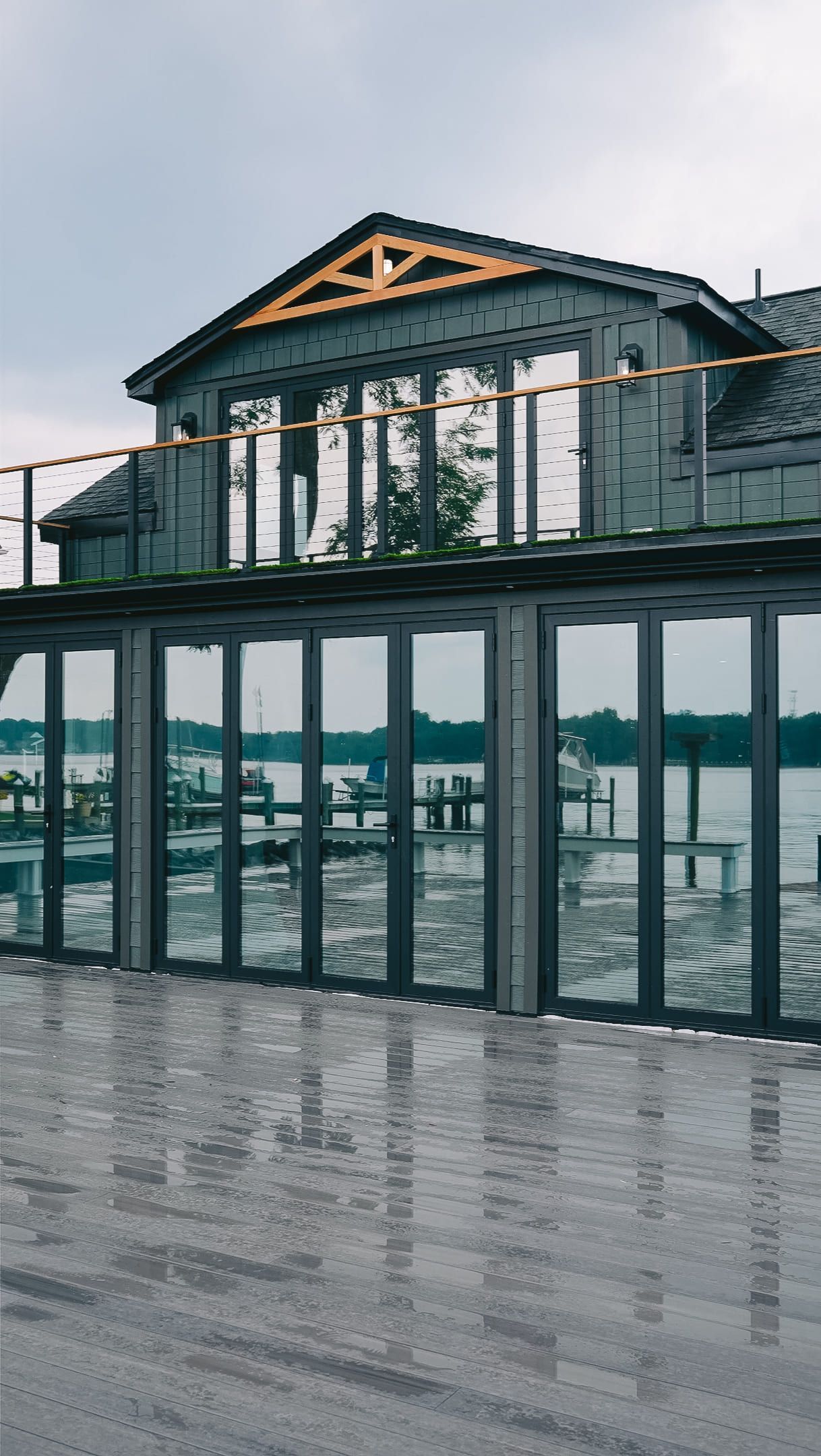 Modern glass-fronted building with a peaked roof on a rainy waterfront pier