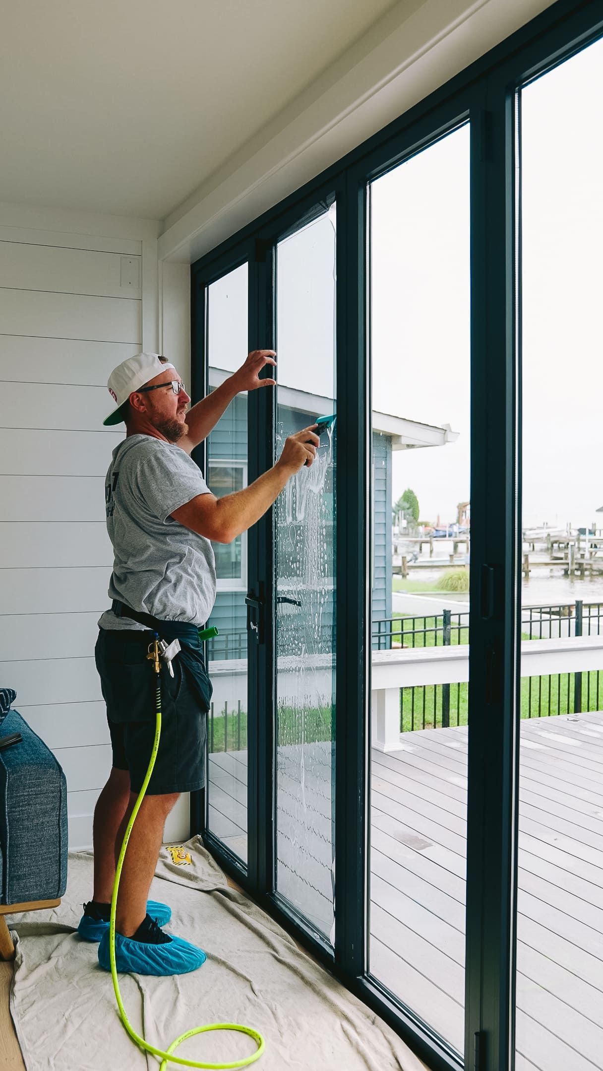 Worker installing window film on tall glass doors inside a bright room
