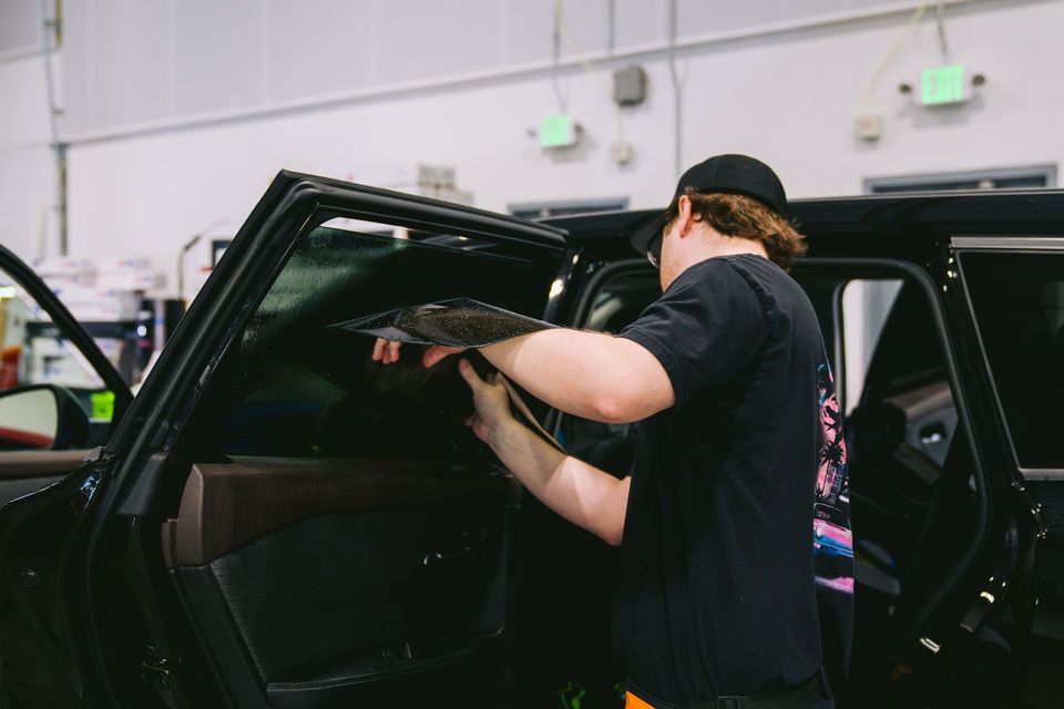 Person installing a car seat in a black SUV inside a workshop