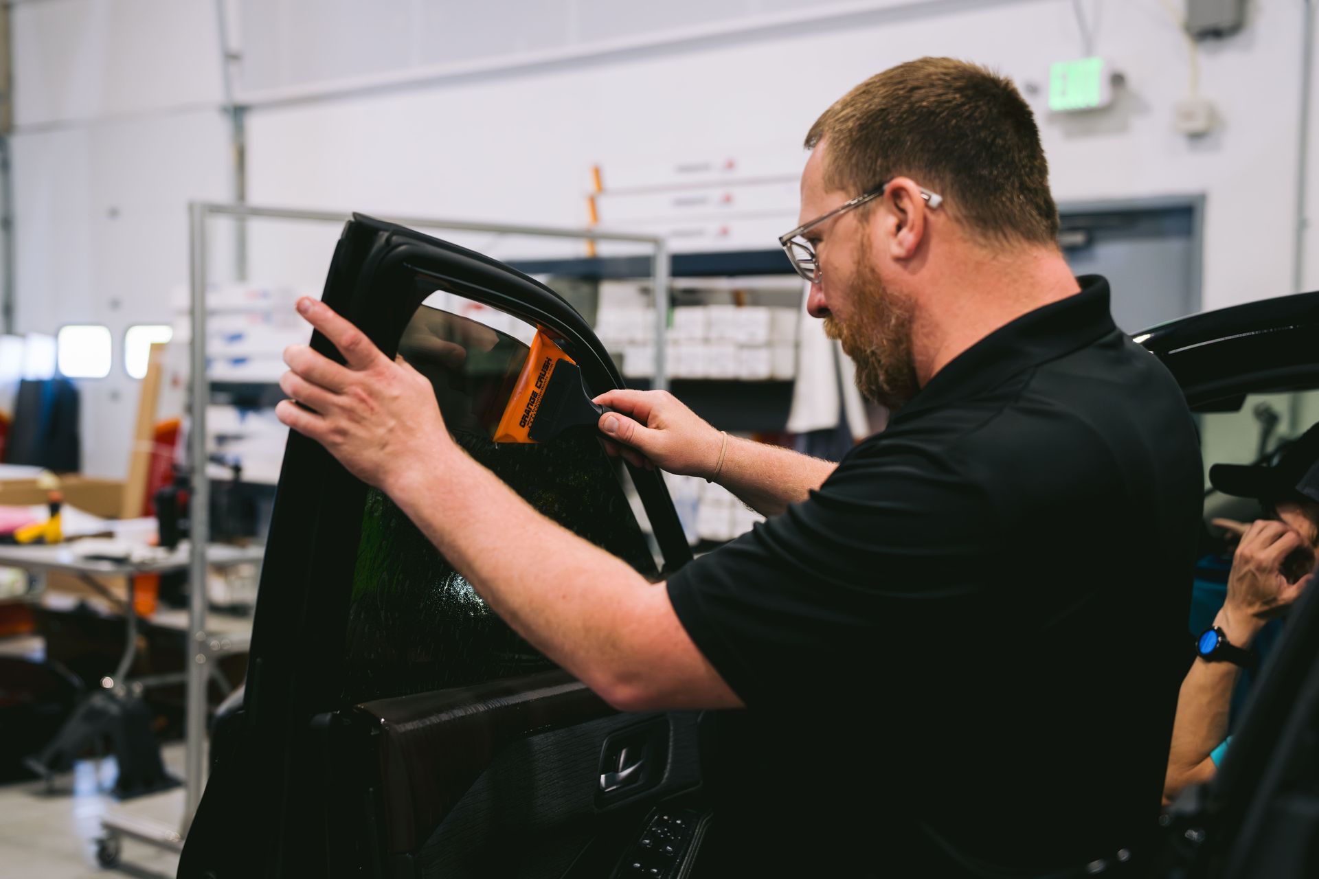 Man inspecting a car door panel in an auto workshop