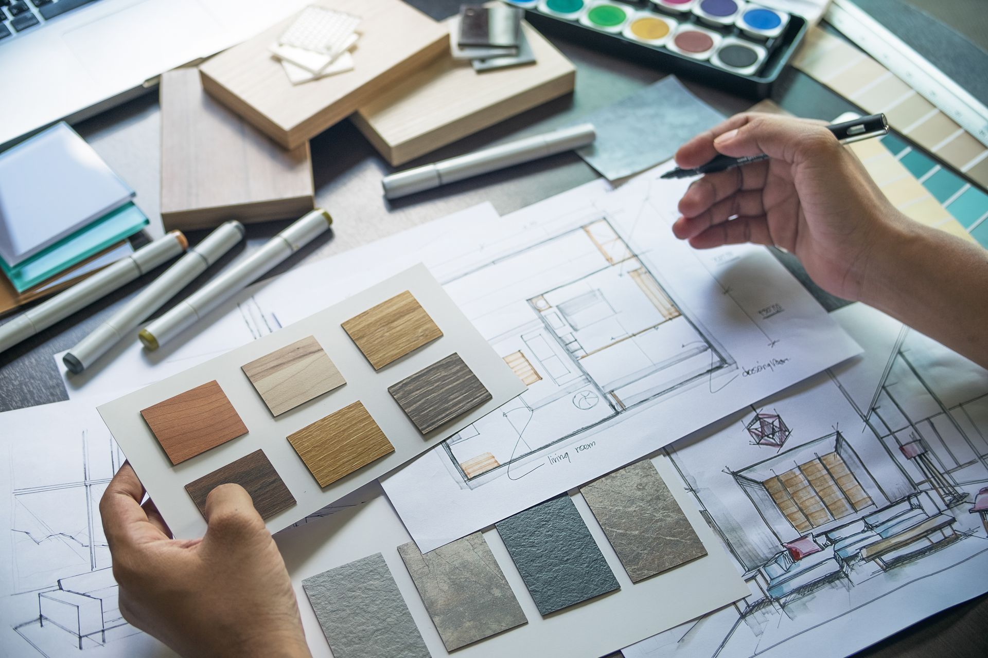 Hands holding wood samples, sketching on blueprints with paint and design tools. Hands holding wood samples, sketching on blueprints with paint and design tools.