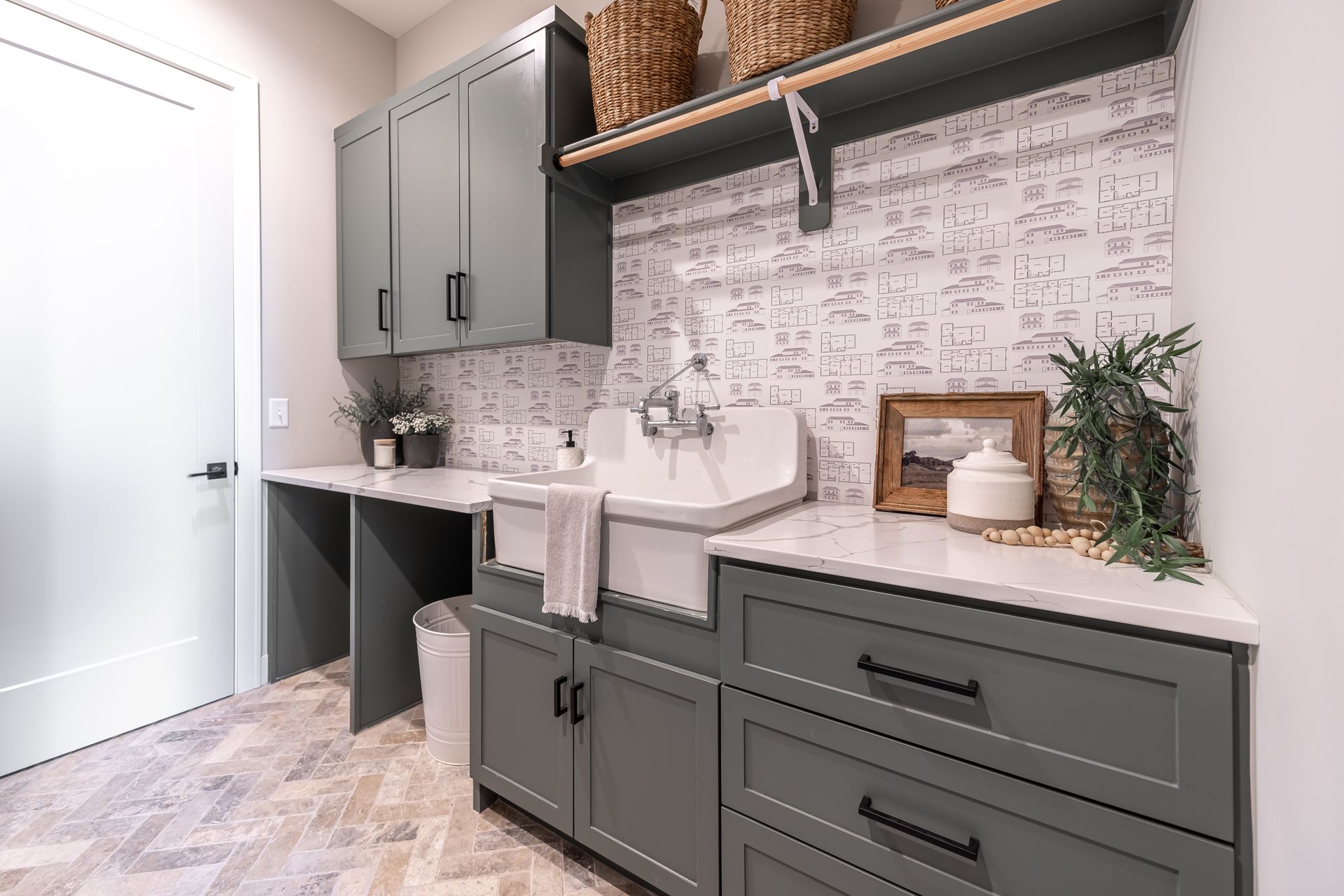 Gray laundry room with cabinetry, sink, and textured backsplash. Baskets on a shelf. Gray laundry room with cabinetry, sink, and textured backsplash. Baskets on a shelf.