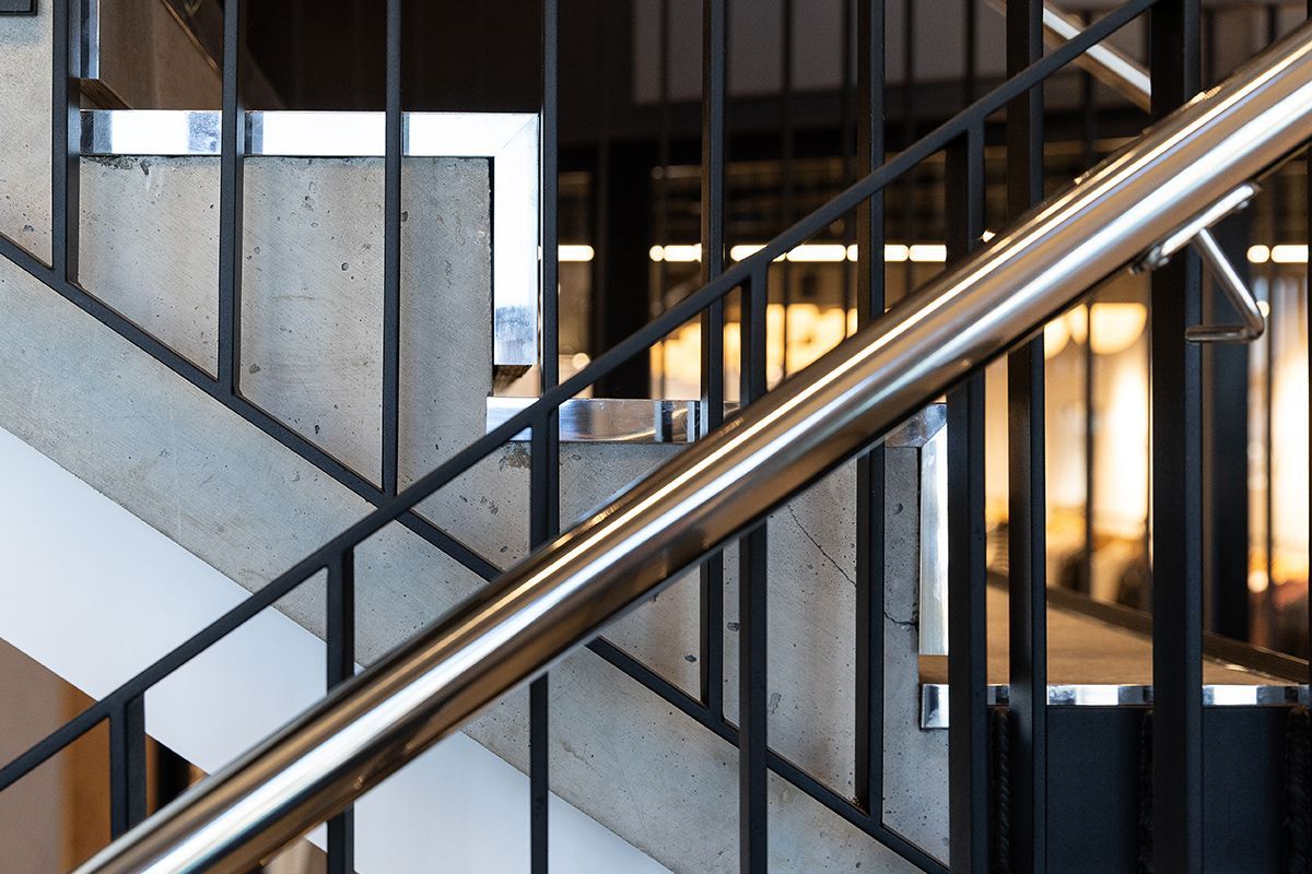 Stainless steel handrail on concrete stairs with black metal railings.