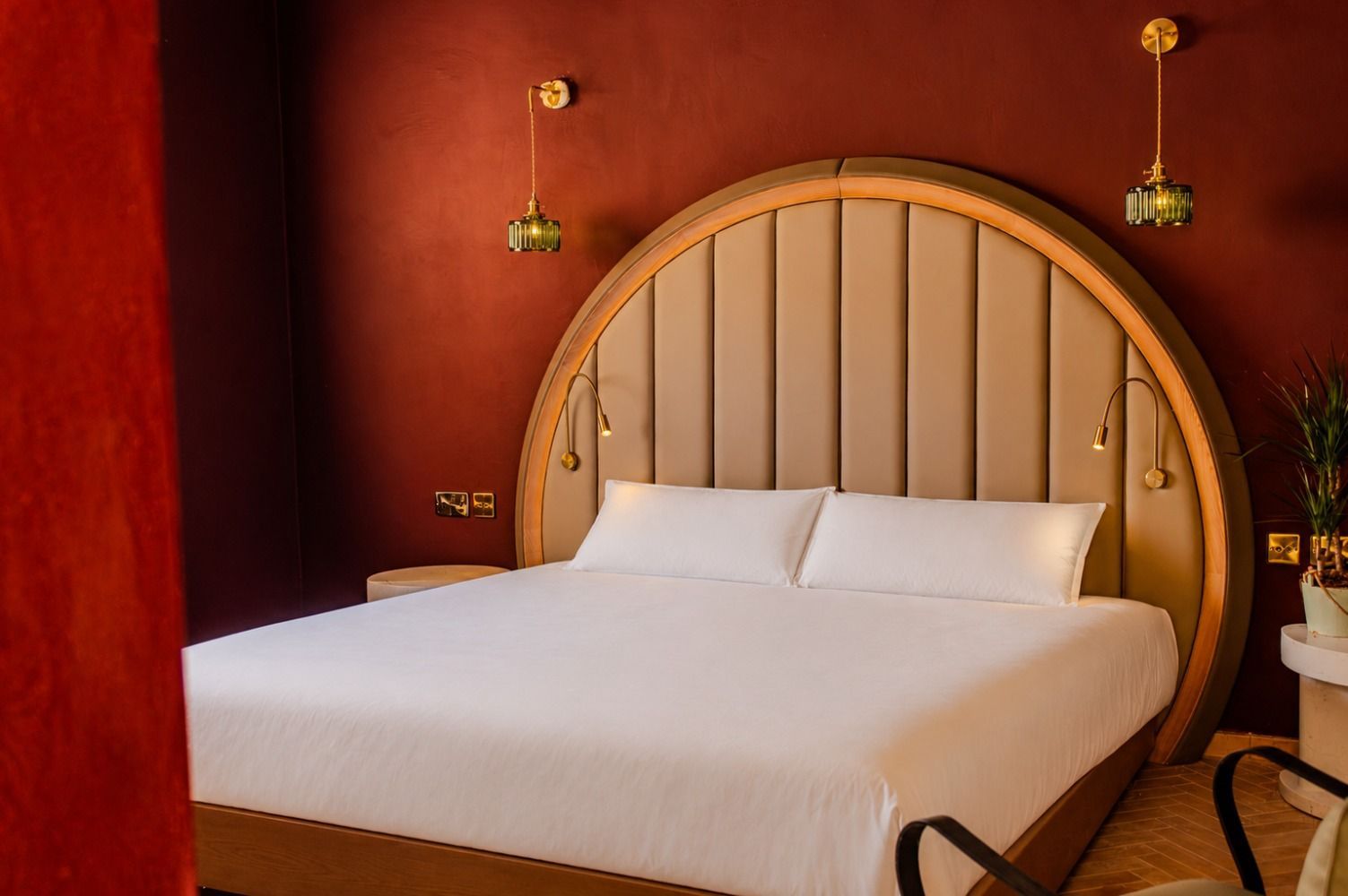 Luxurious bedroom with a white bed, arched beige headboard, and red walls