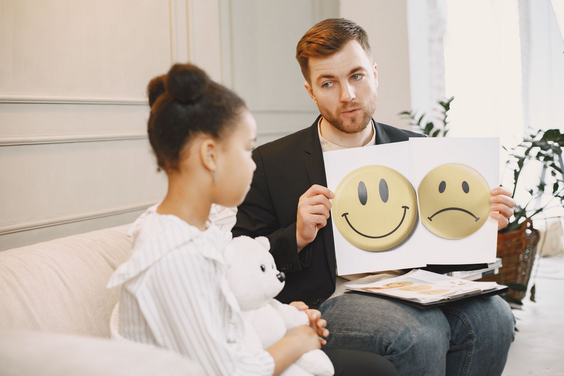 Therapist showing happy and sad face cards to a seated client in a counseling office